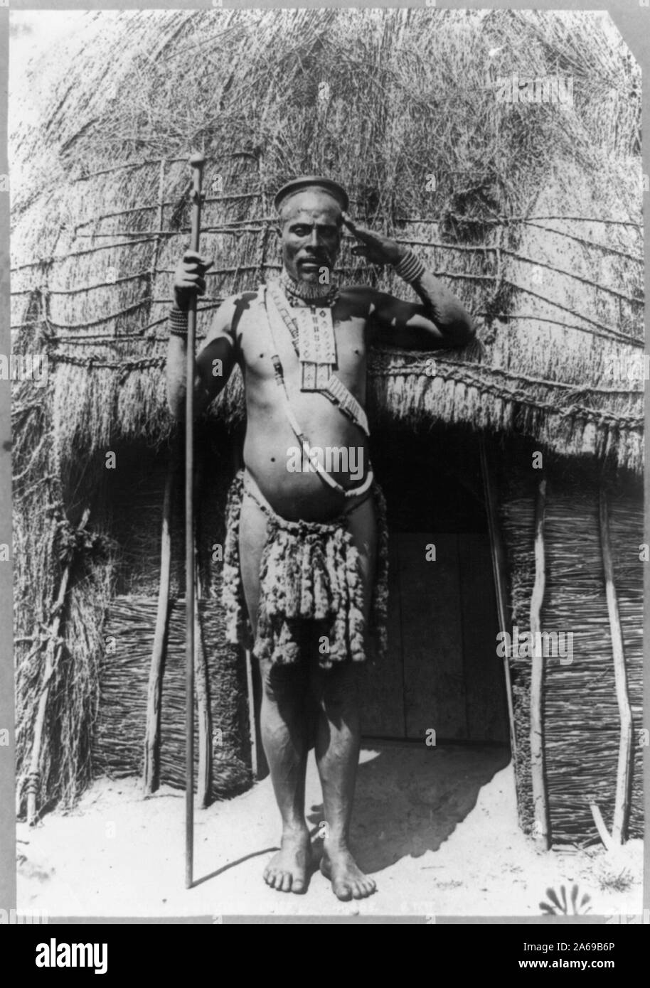 Zulu chief, South Africa Abstract: Man in native dress standing in front of hut. Stock Photo