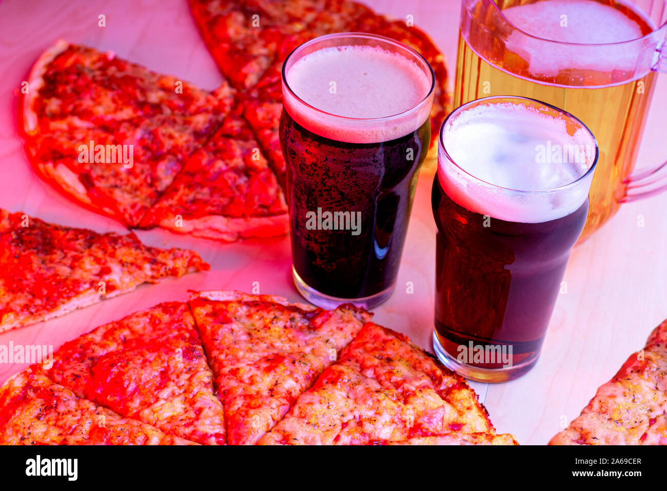 Glasses of beer, Beer Jug and a pizza with a red lights at night Stock Photo
