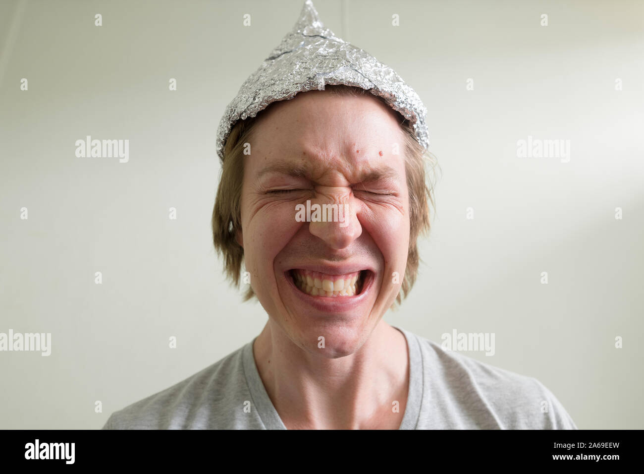 Face of stressed young man with tin foil hat getting scared inside the ...
