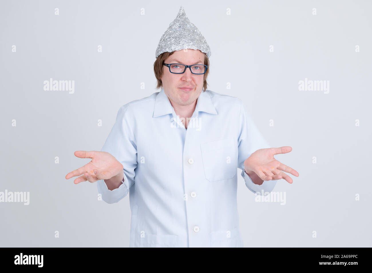 Young man doctor with tinfoil hat shrugging shoulders Stock Photo
