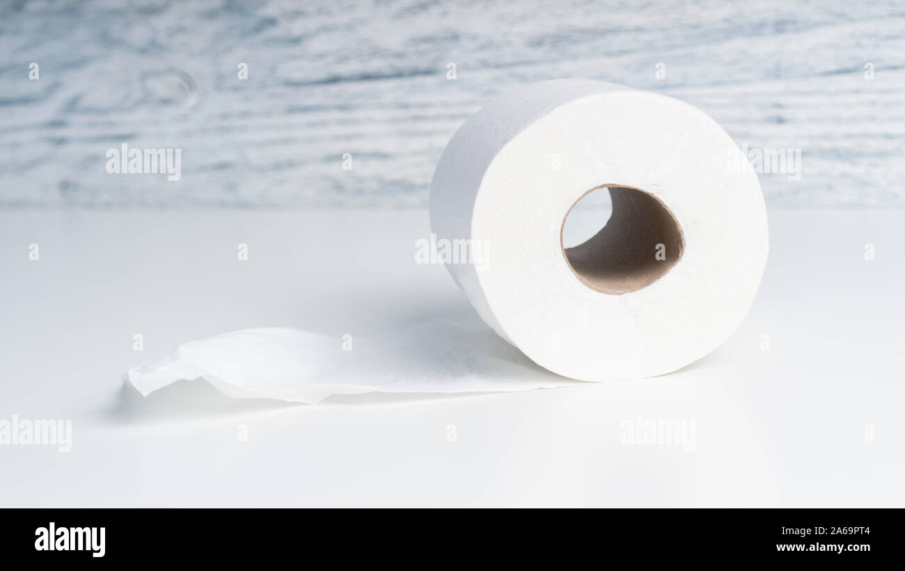 Toilet paper roll on a white table against a background of a wooden structural blue wall. The concept of using bio materials for hygiene Stock Photo