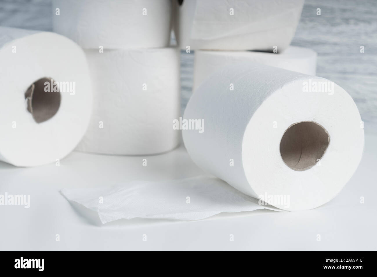 A pile of toilet paper rolls on a white table on a background of blue ...