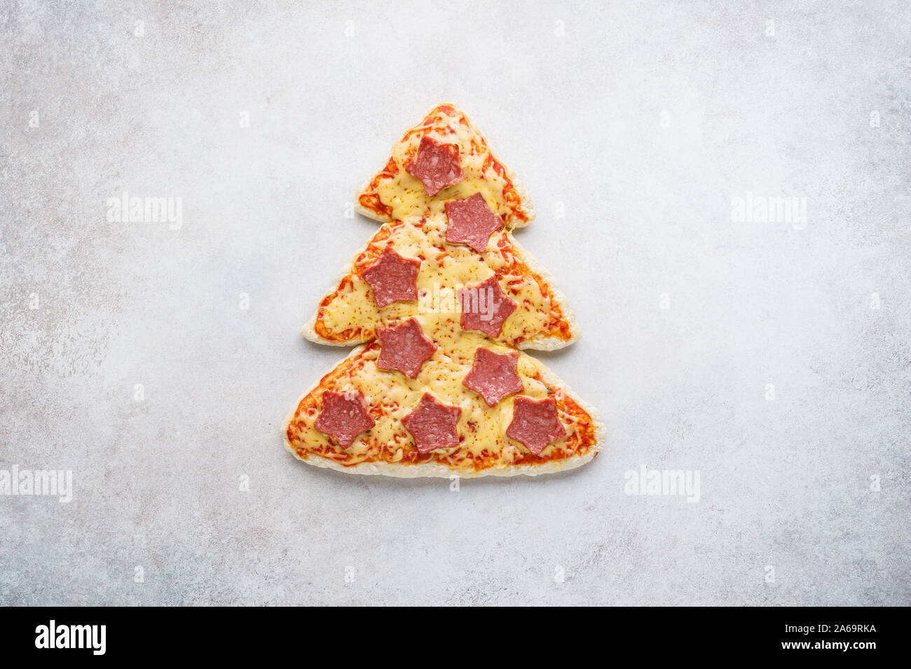Pizza shaped as Christmas tree decorated with stars made of pepperoni