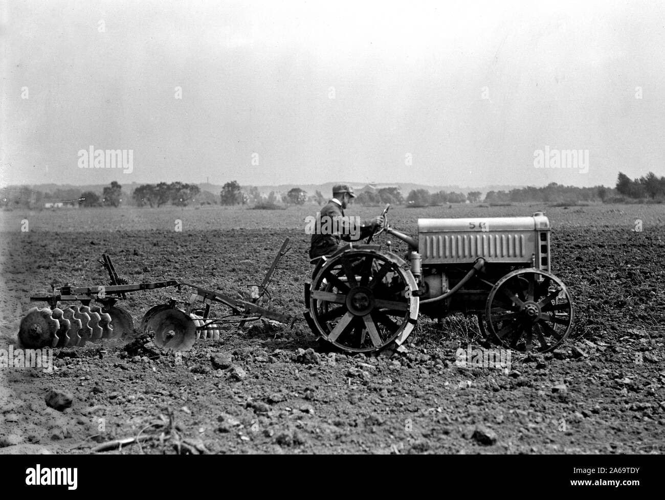 Farmer driving Ford Tractor in field ca. 1917 Stock Photo