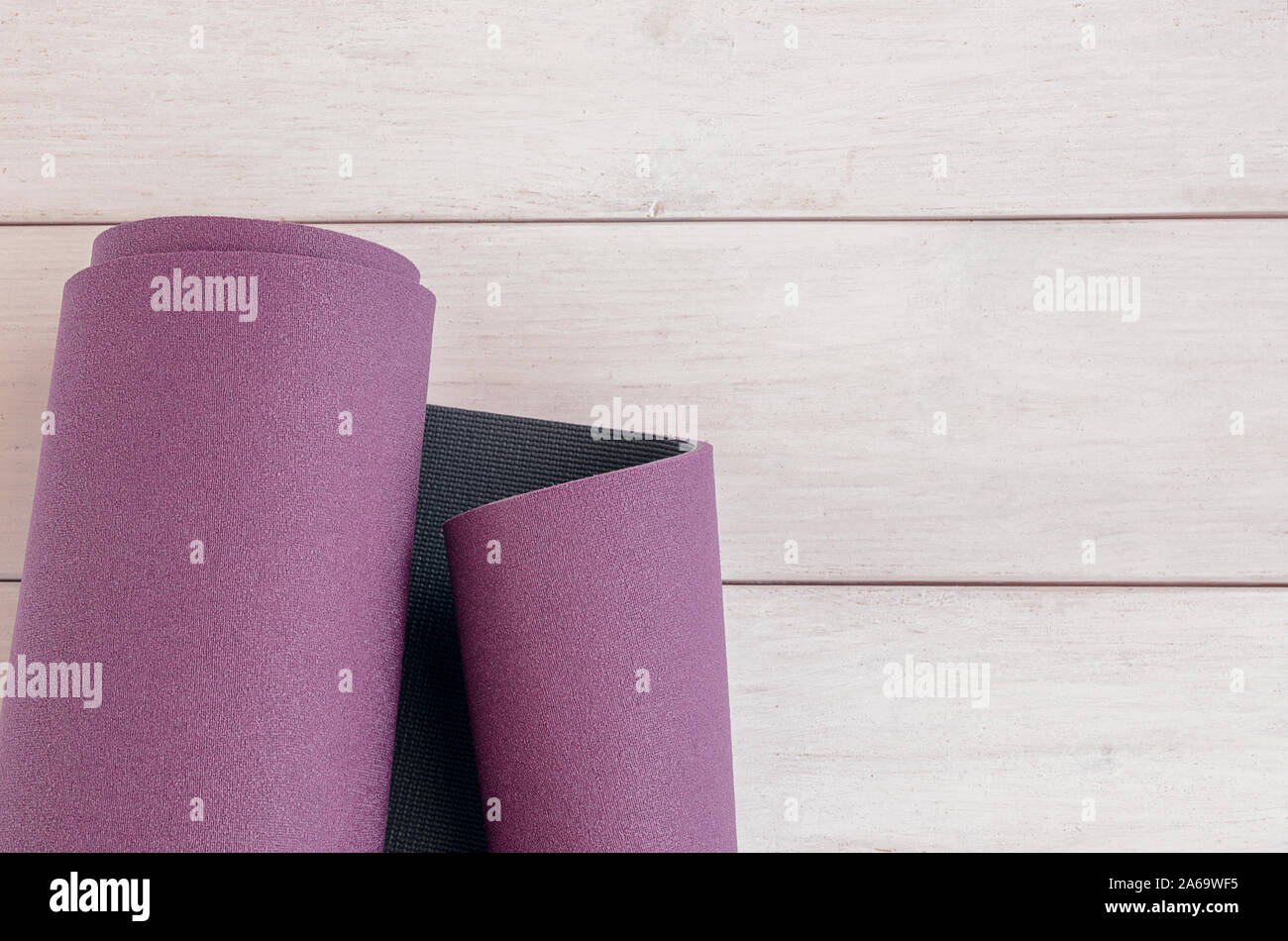 Yoga rolled exercise mat on white wooden background with copy space. Concept for ashtanga yoga practice. Stock Photo