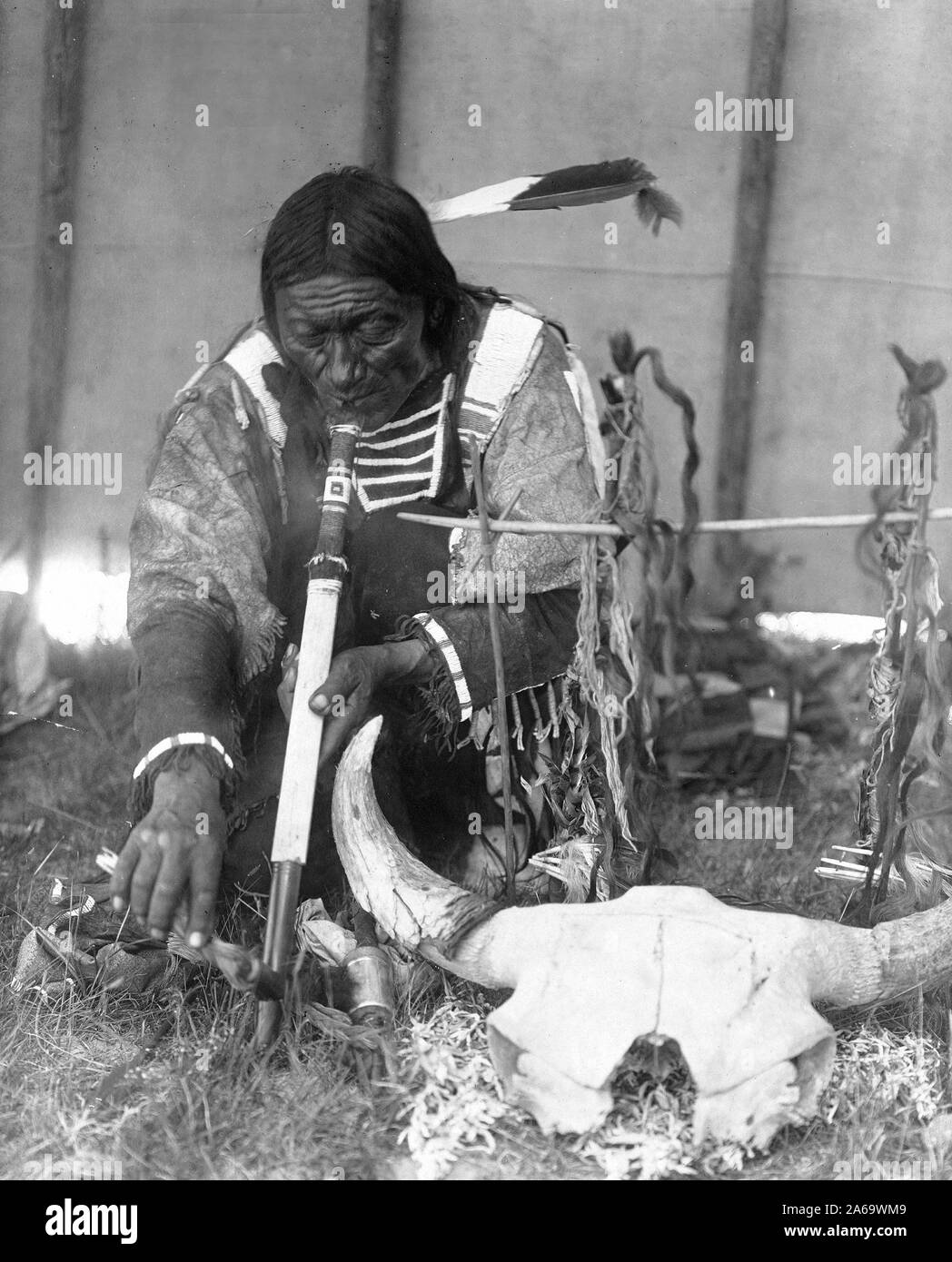 Edward S. Curtis Native American Indians - Dakota man with calumet kneeling by altar inside tipi ca. 1907 Stock Photo