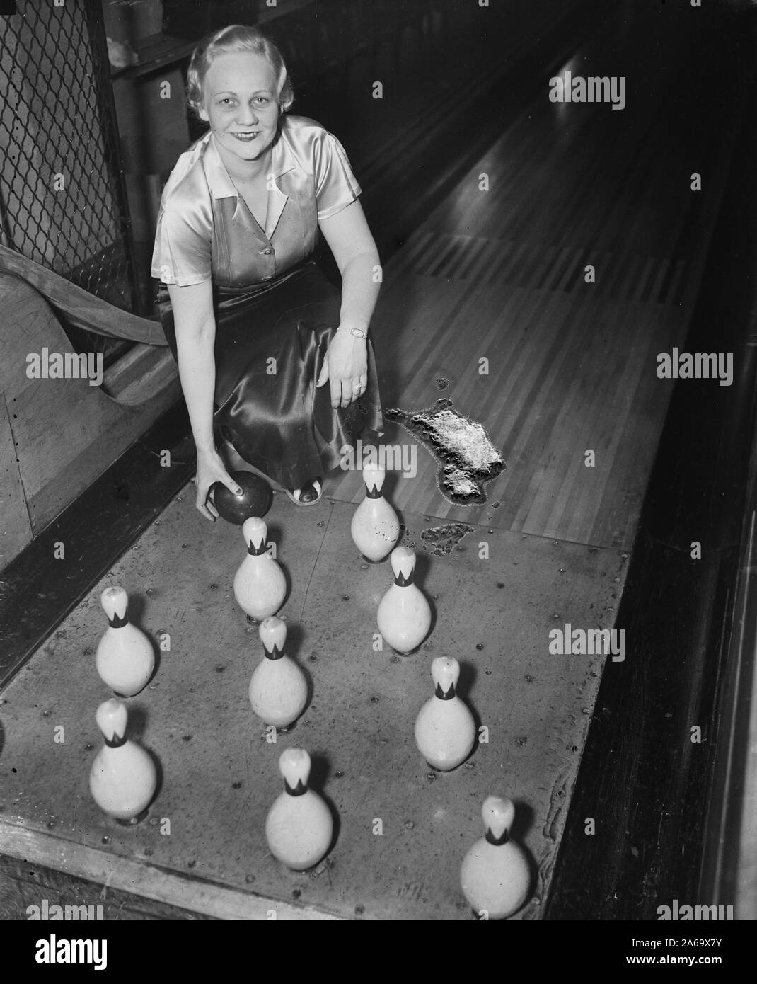 Woman in a bowling alley holding ball by the pins ca. 1936 Stock Photo
