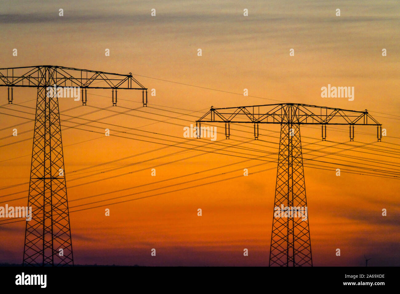 High voltage power line in Sunset Pylons transmission line Germany energy Stock Photo