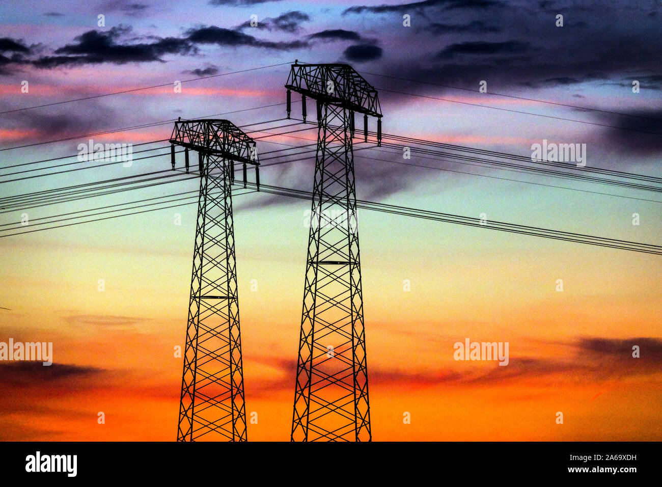 High voltage power lines sunset pylons transmission energy Germany Global warming sky Stock Photo