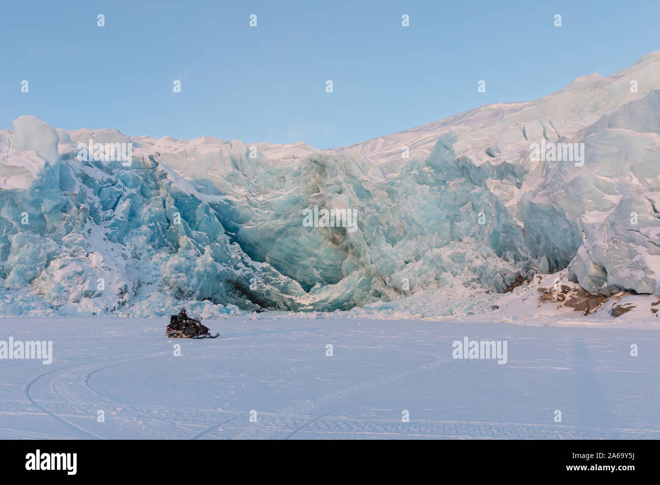 Svalbard, Norway - March 2019: Man on snowmobile in front of Nordenskiold glacier on Svalbard, Norway. Stock Photo