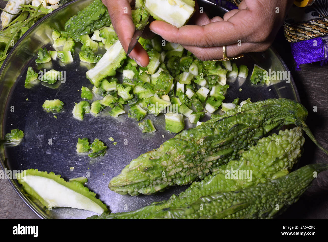 A woman,s hand and pieces of bitter gourd cutting bitter gourd with a knife Stock Photo