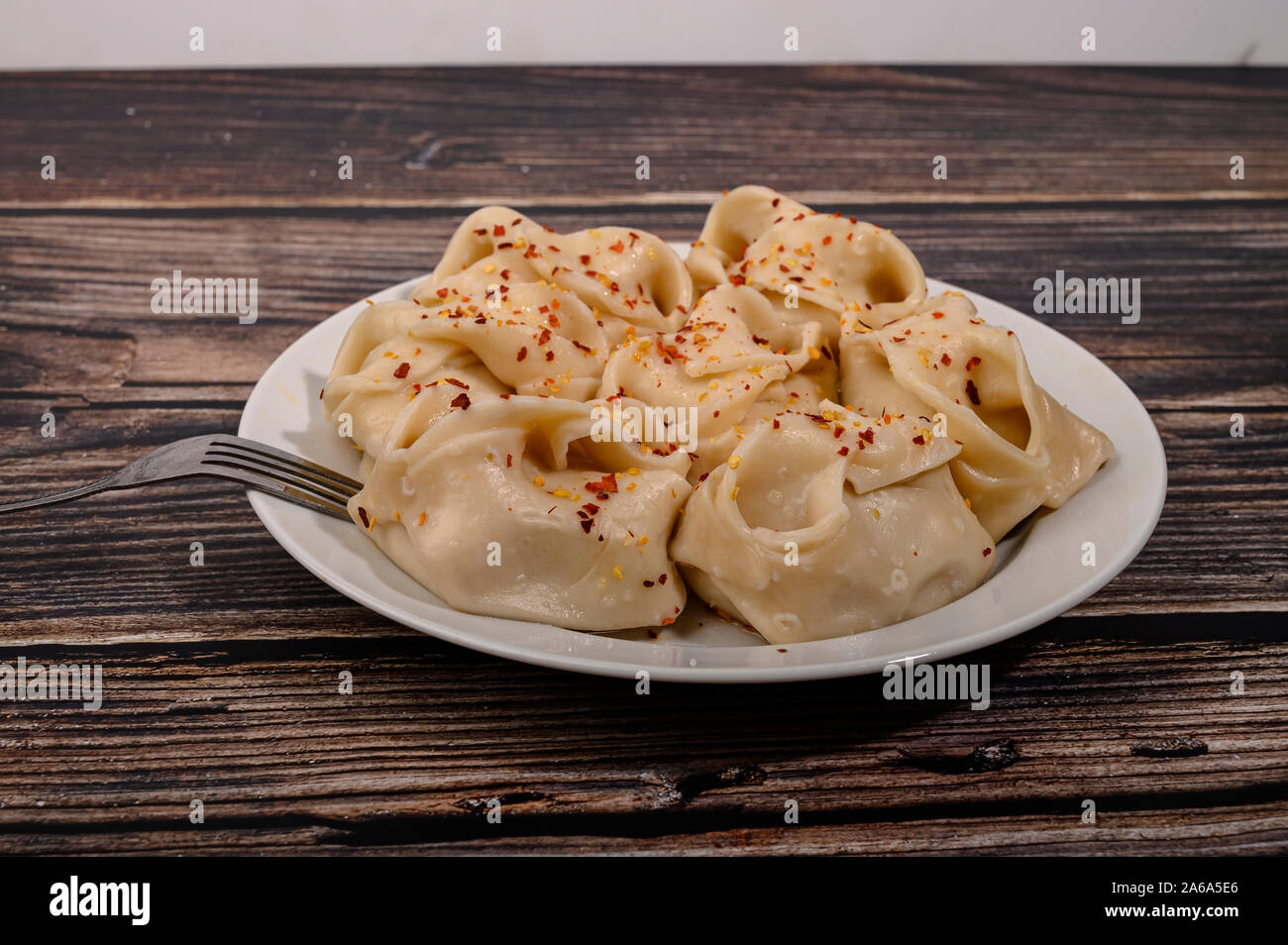 Boiled manti with beef on a plate with spices on a wooden table Stock Photo