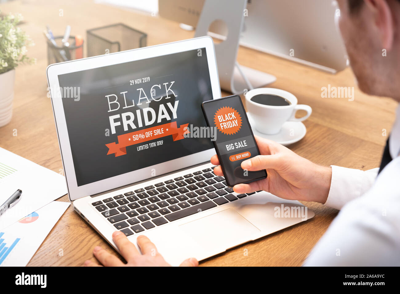 Black Friday promotion sale on laptop and phone screen. Young man doing shopping online Stock Photo