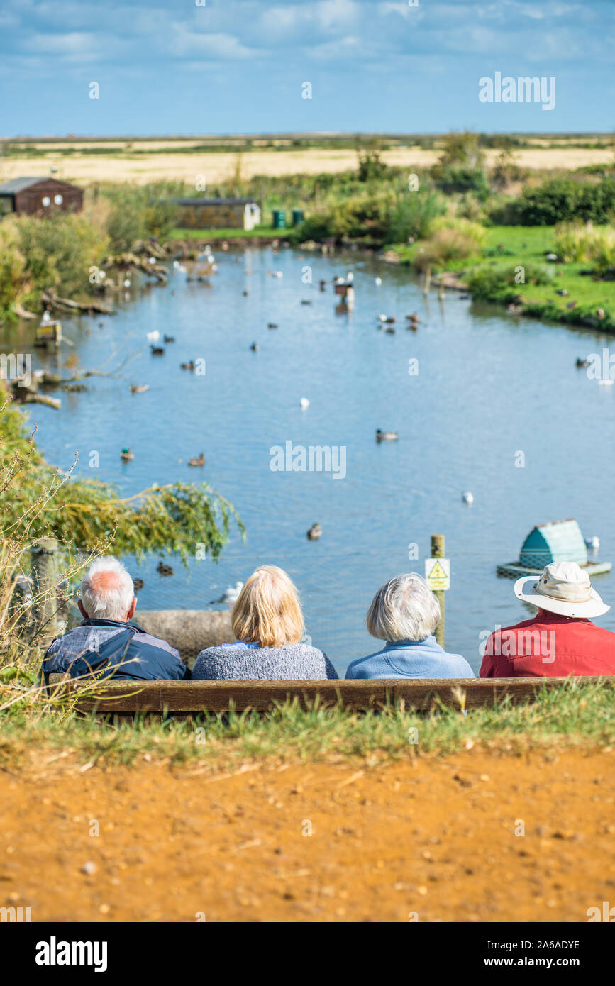 Elderly people enjoying the tranquility of Blakeney Conservation Duck Pond near the North Norfolk coast in East Anglia, England, UK. Stock Photo