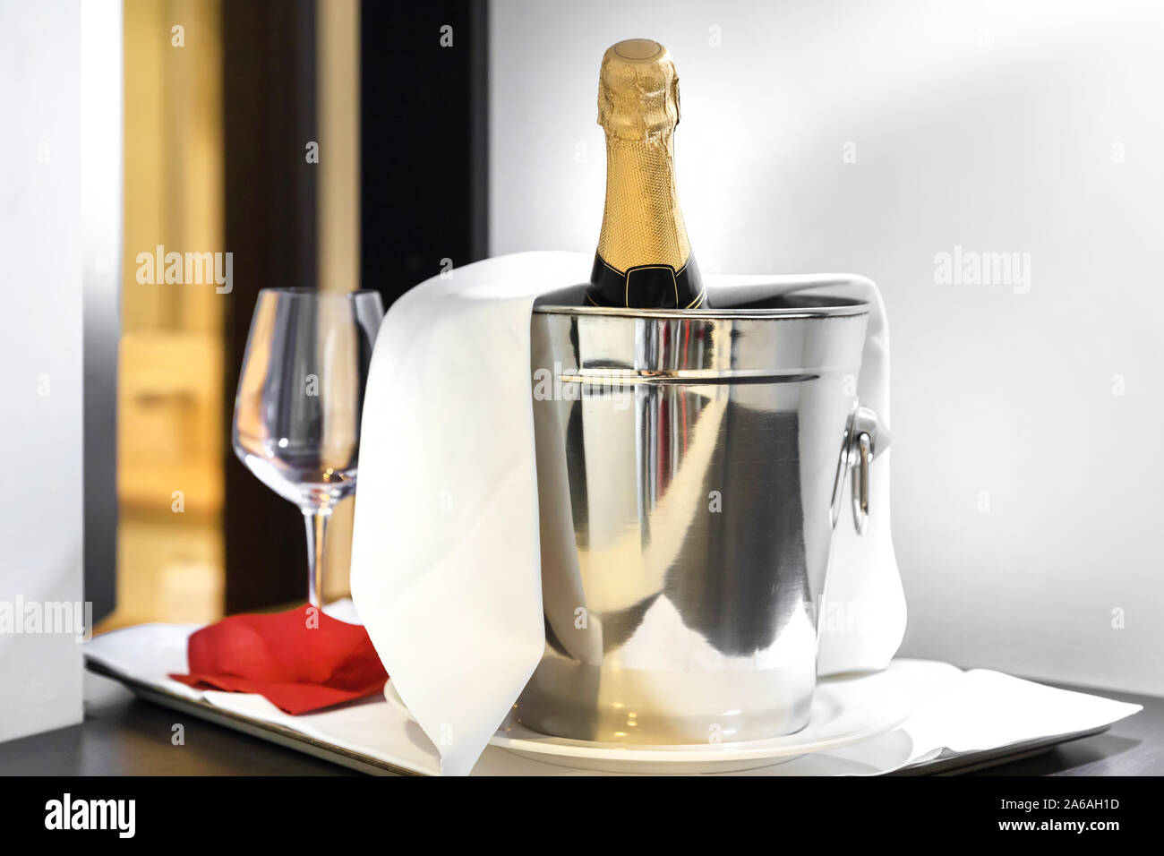 Bottle of cold wine or champagne in ice bucket on white table at hotel room. Wedding reception, holiday concept. Copy space. Stock Photo