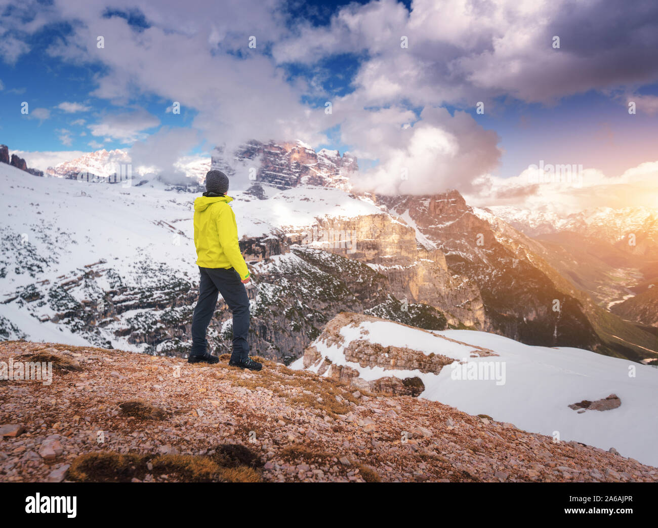 Young man in yellow jacket on the hill and snowy mountains Stock Photo