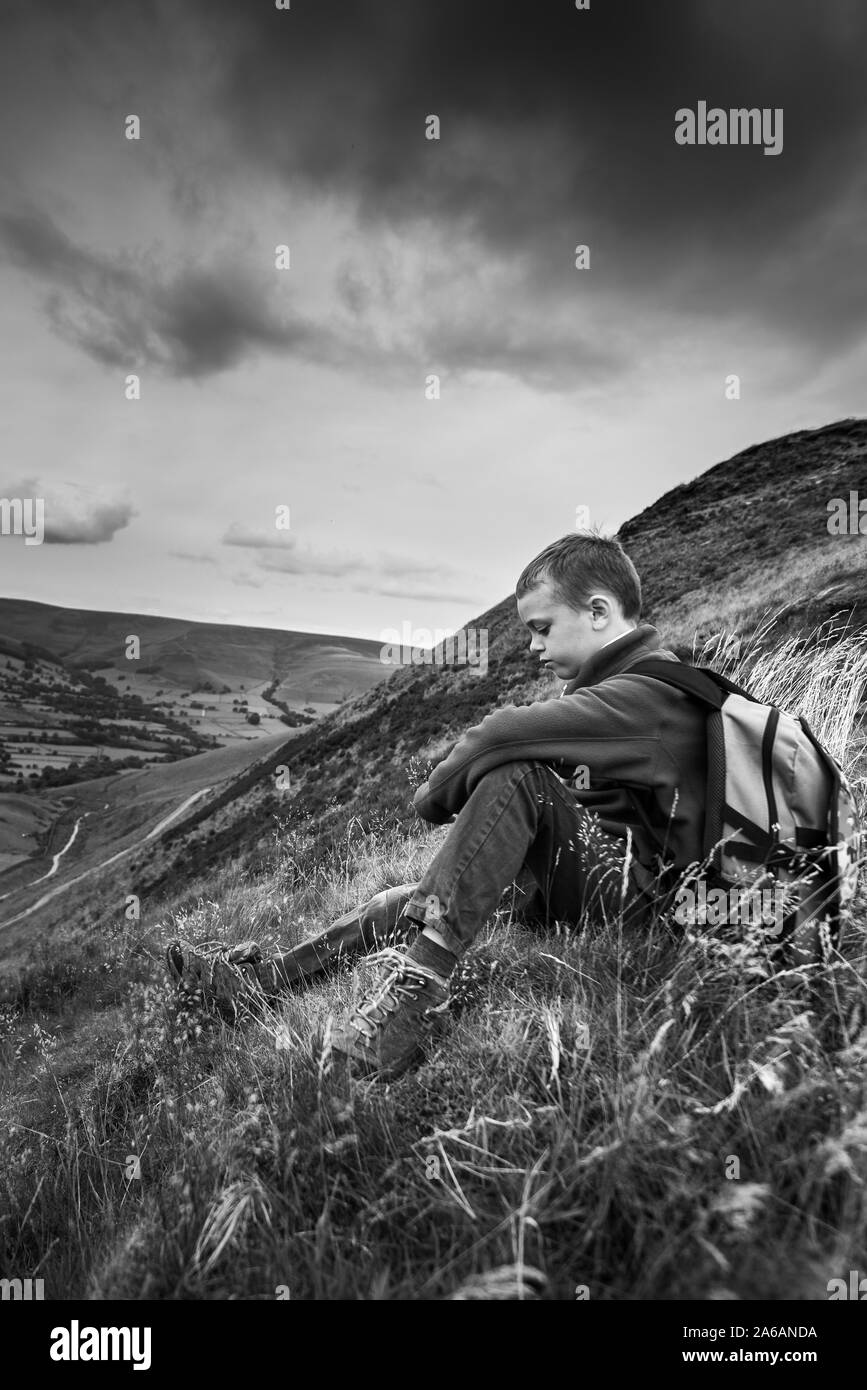 A little boy with ADHD, Autism, Aspergers Syndrome sitting lonely, isolated while out hiking and mountain climbing, the Great Ridge, mental illness, Stock Photo