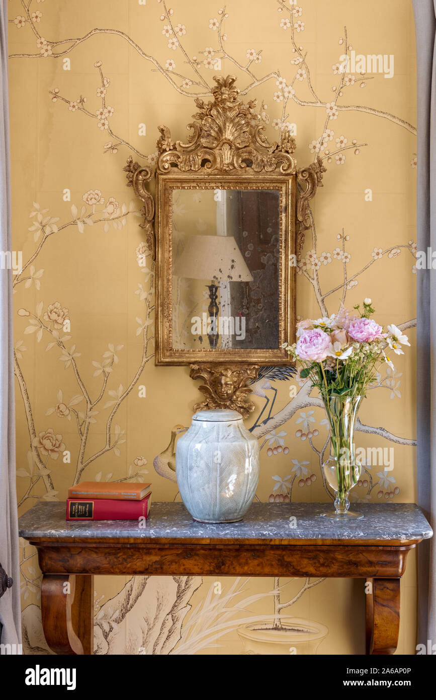 Decorative gilt framed mirror above marble console with de Gournay wallpaper Stock Photo