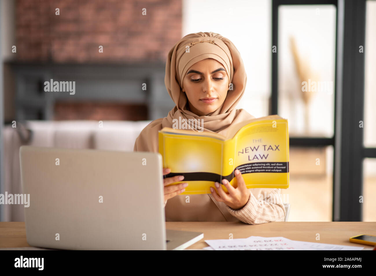 Beautiful Muslim girl reading a book about tax law Stock Photo