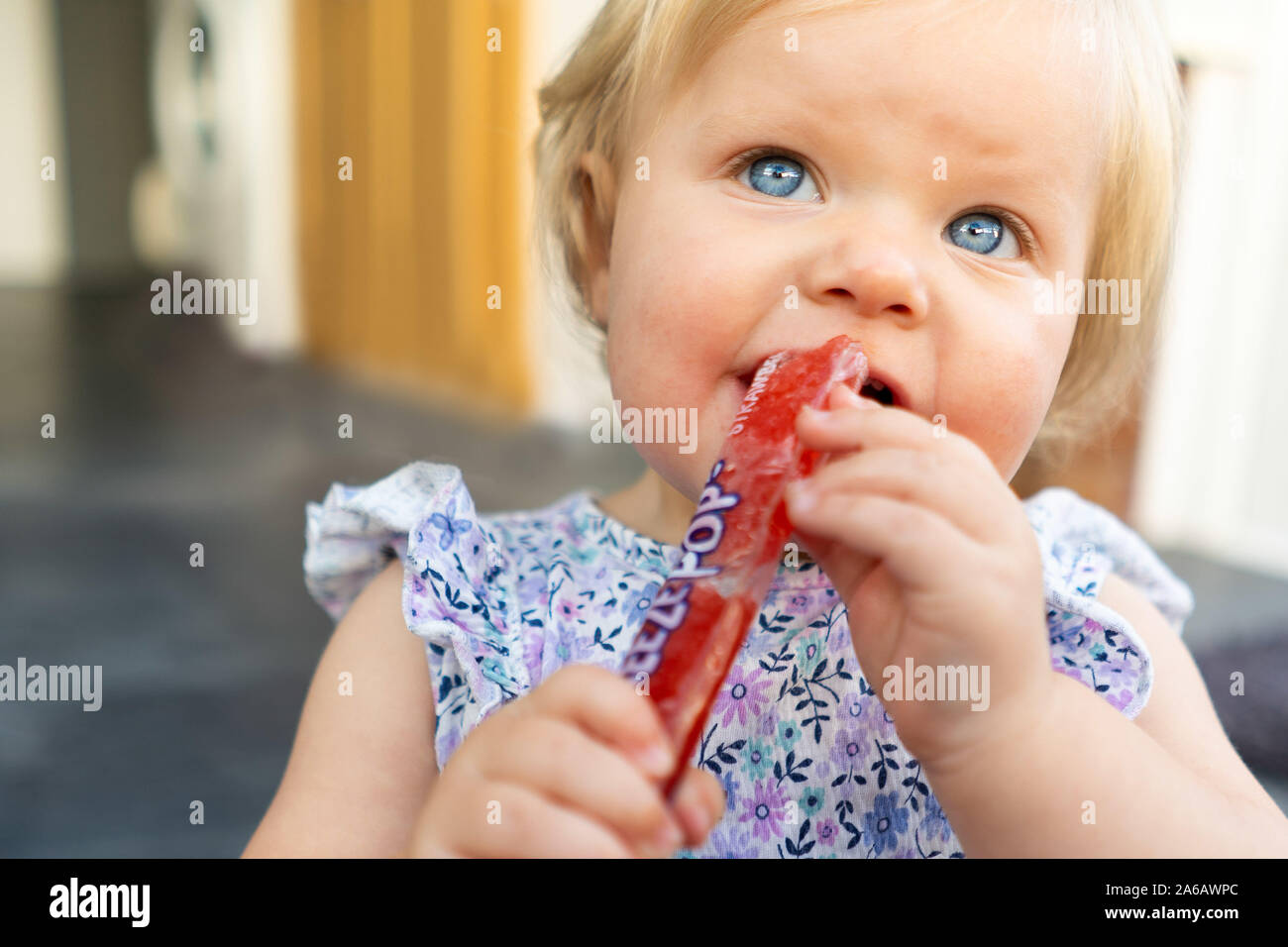 A beautiful little baby girl eating an ice pole to help with her
