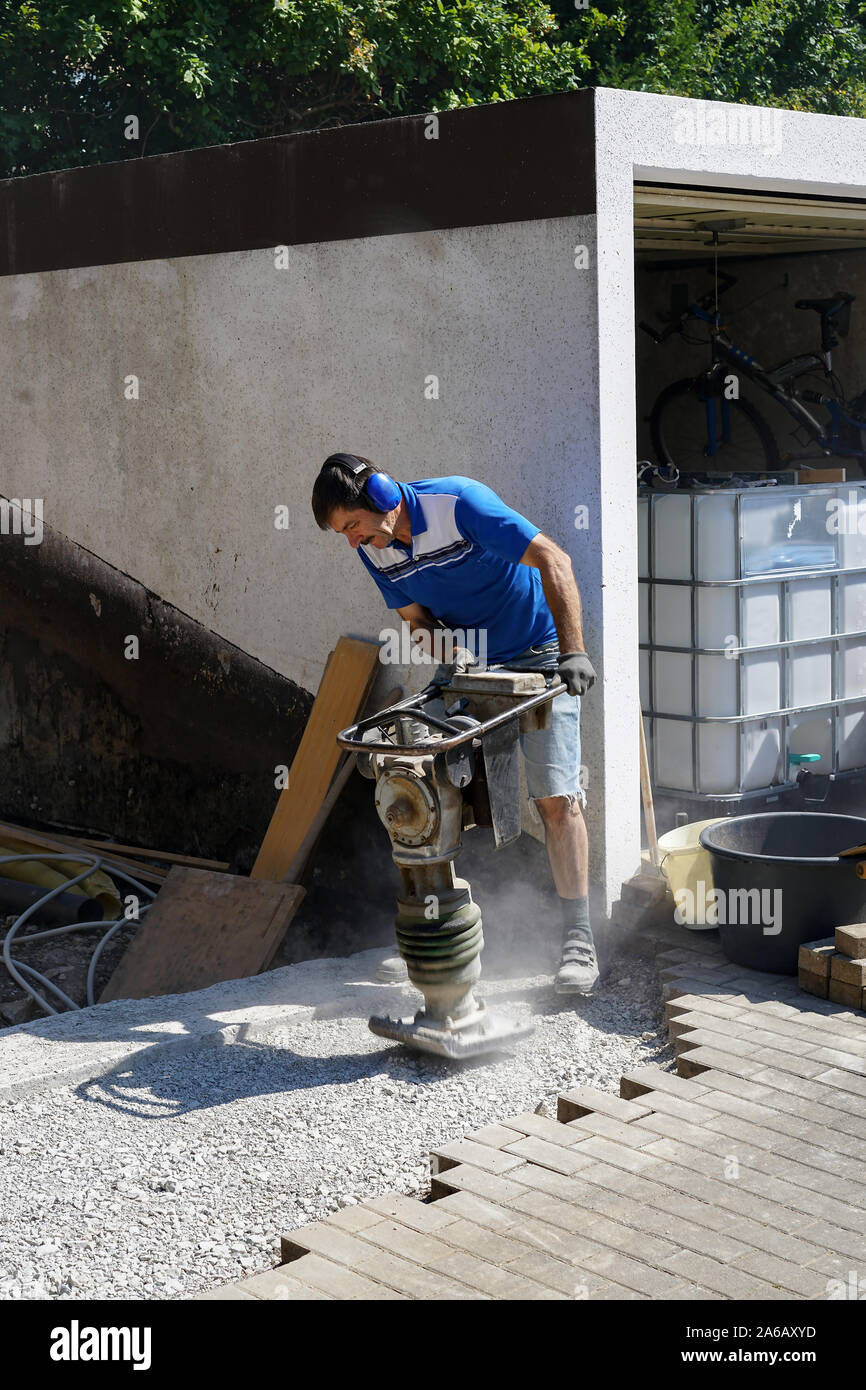 Construction worker compacting soil using compactor. Work with tamping
