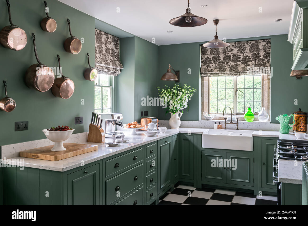 Green paintwork in 1930s Art Deco style kitchen with wall mounted copper pots Stock Photo