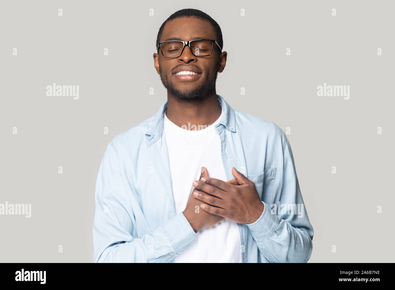 head-shot-smiling-african-american-man-holding-hands-on-chest-stock