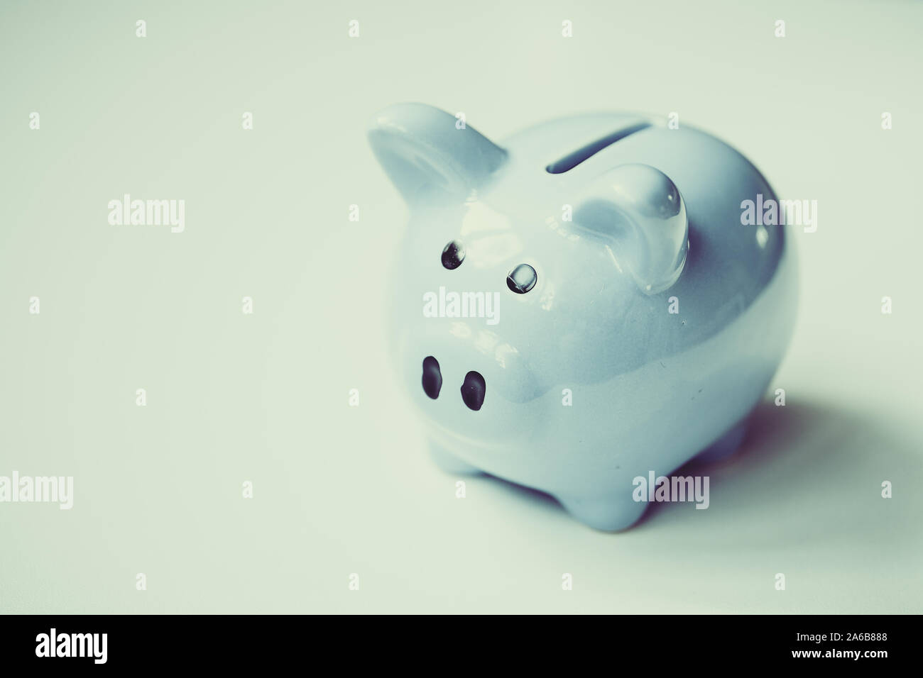 Blue piggy bank standing on white background with copy space. Tonet ...