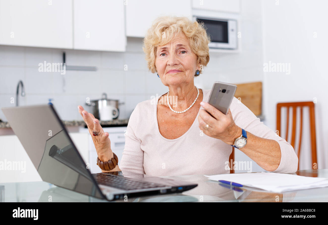 Difficult Using Computer Senior woman has difficulties using computer at her kitchen Stock Photo ...