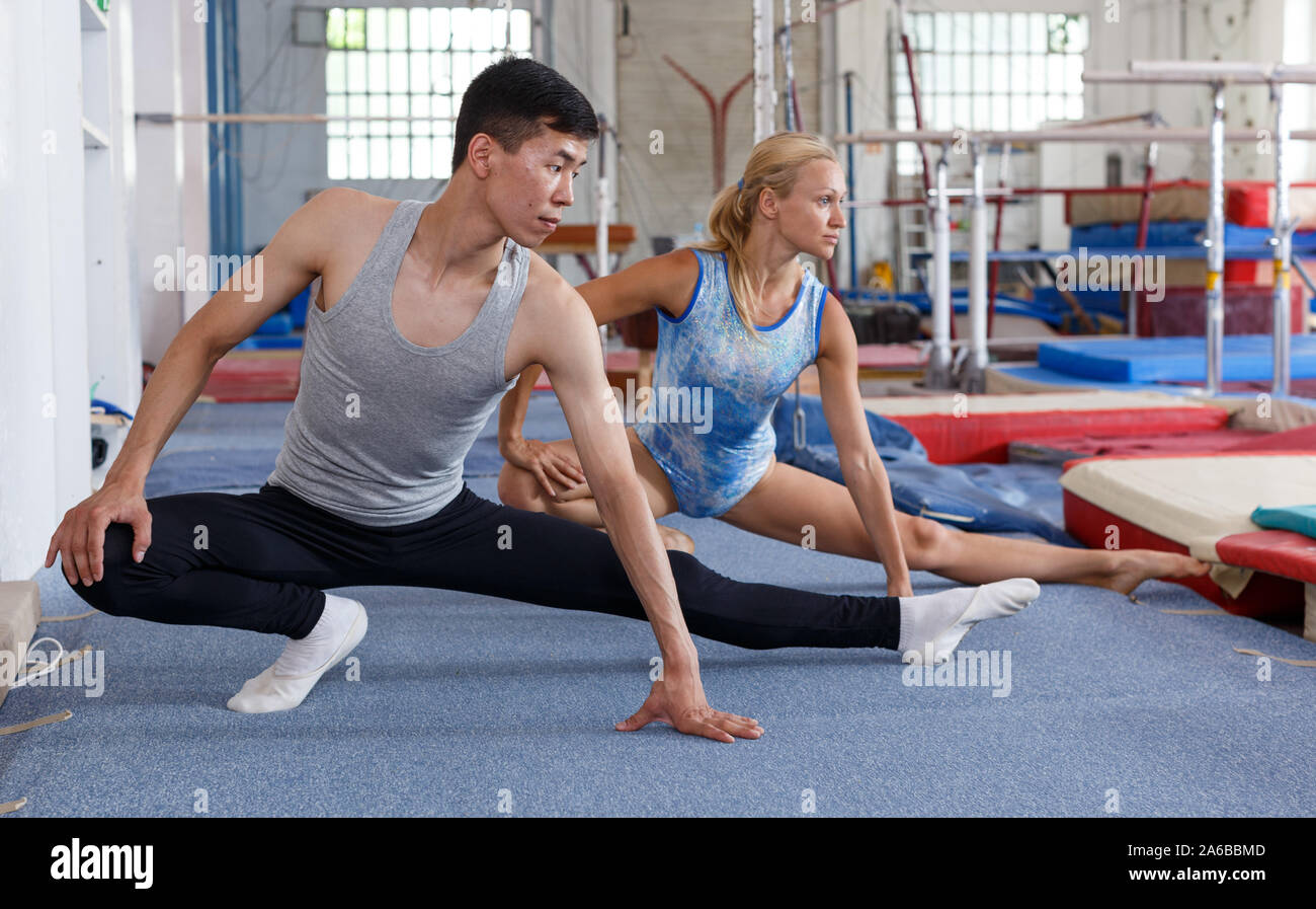 Man and woman doing acrobatic exercises on floor of gym Stock Photo - Alamy