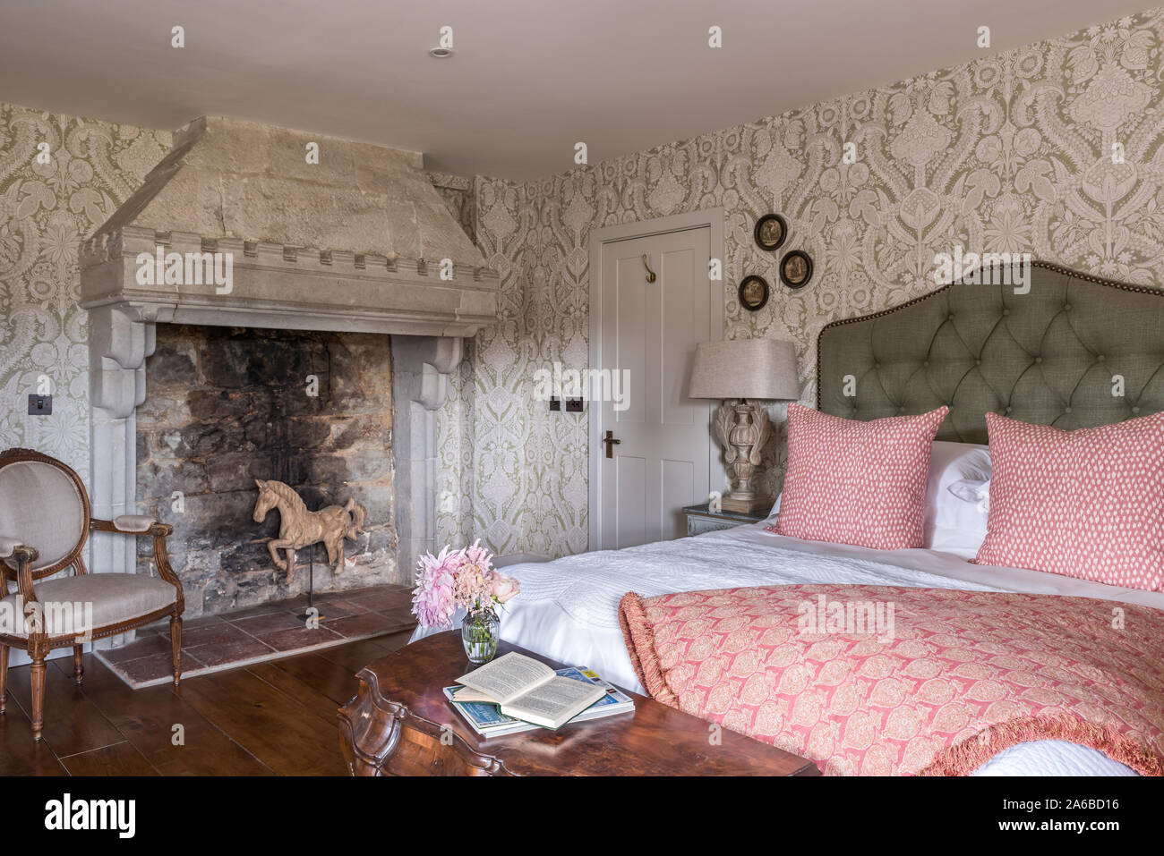 1930s Art Deco style wallpaper and old stone fireplace in bedroom . Stock Photo