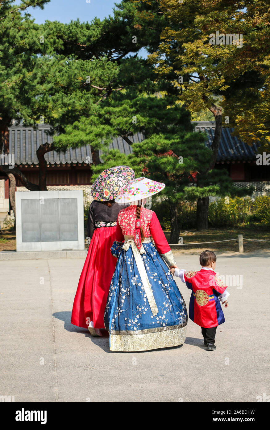 Two young girls with a small boy in national Korean costumes strolling along Chandeokgung Palace, Seoul, South Korea Stock Photo