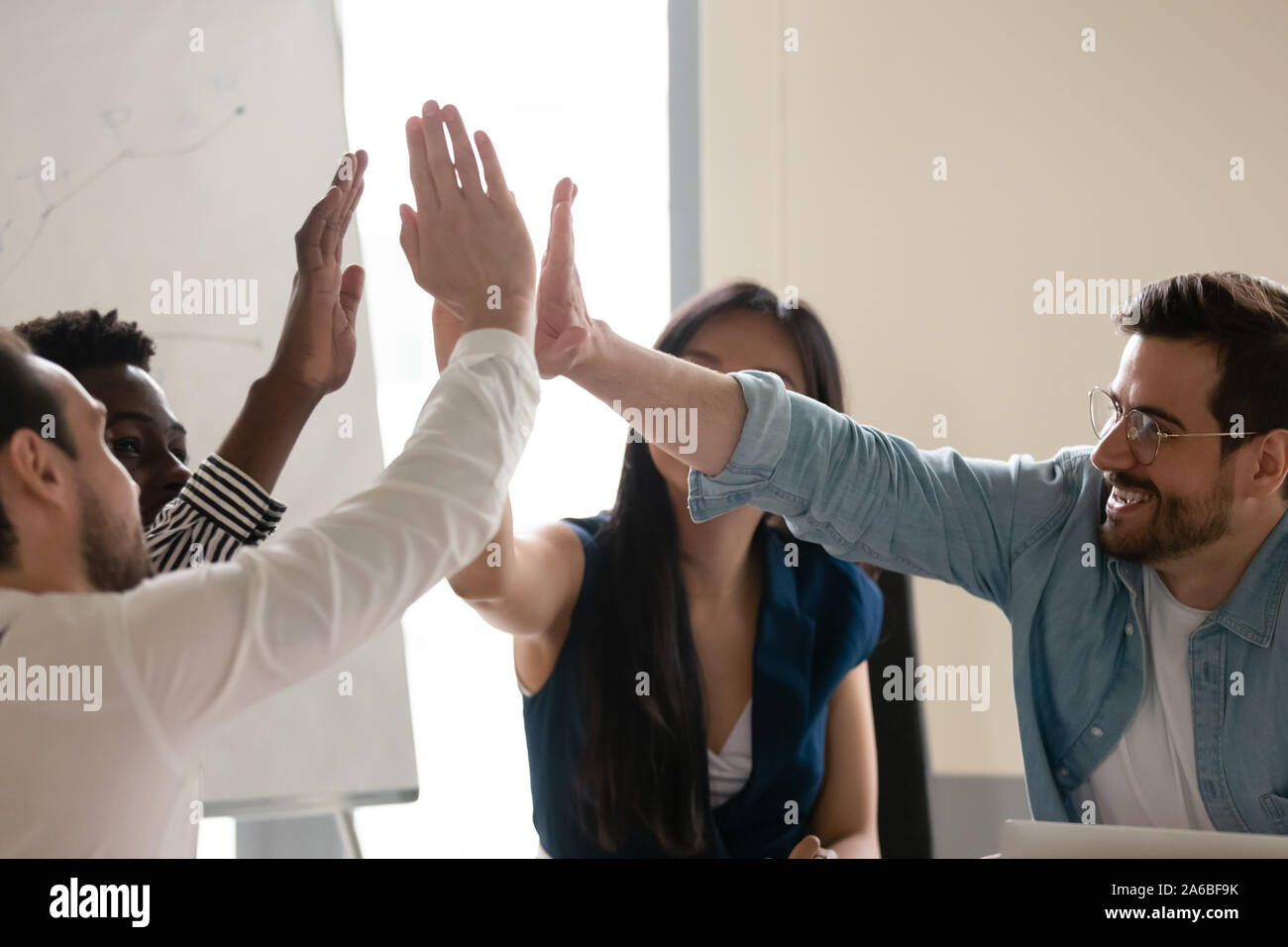 Diverse employees giving high five at meeting, celebrating success ...