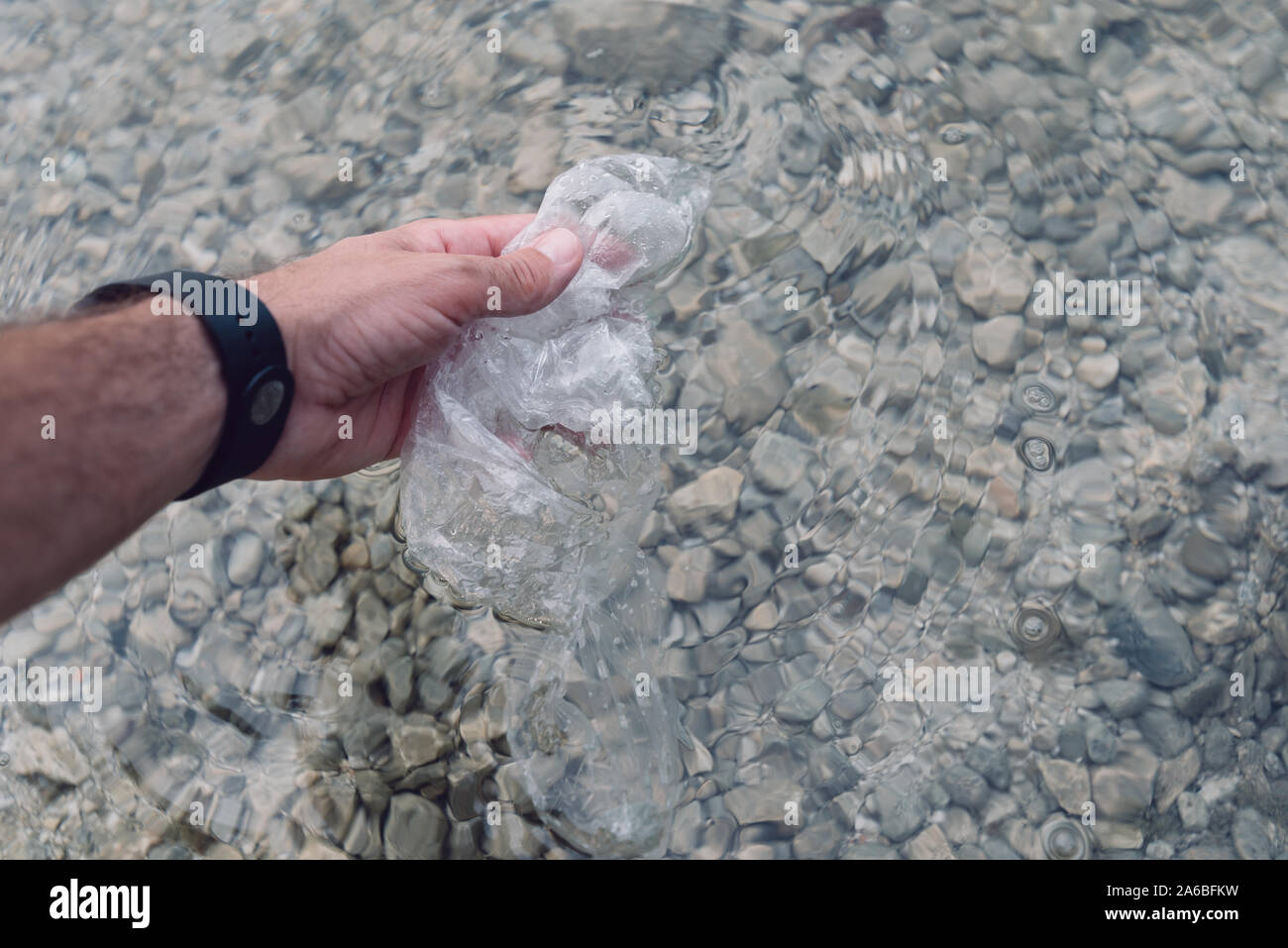 Environmentalist taking plastic bag from water, close up of hand Stock Photo