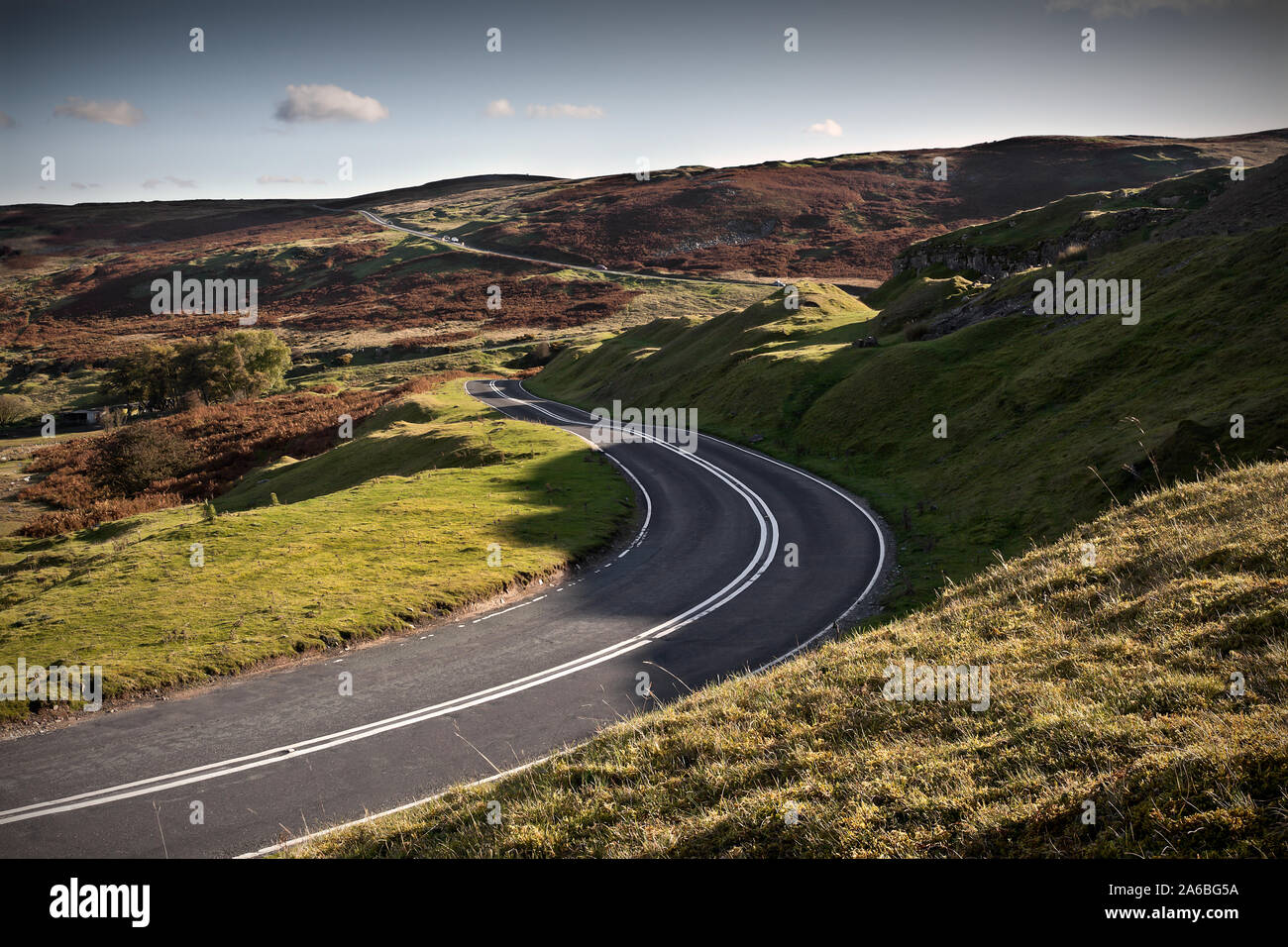 Twisting mountain road in late afternoon light with bend in foreground Stock Photo