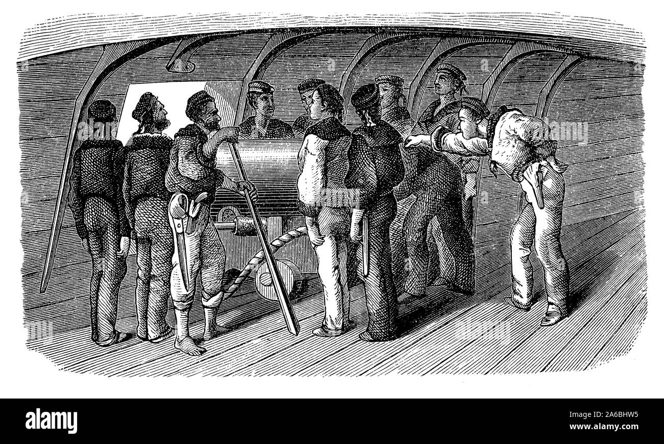 Crew in attendance of a cannon on the gun deck of a warship Stock Photo