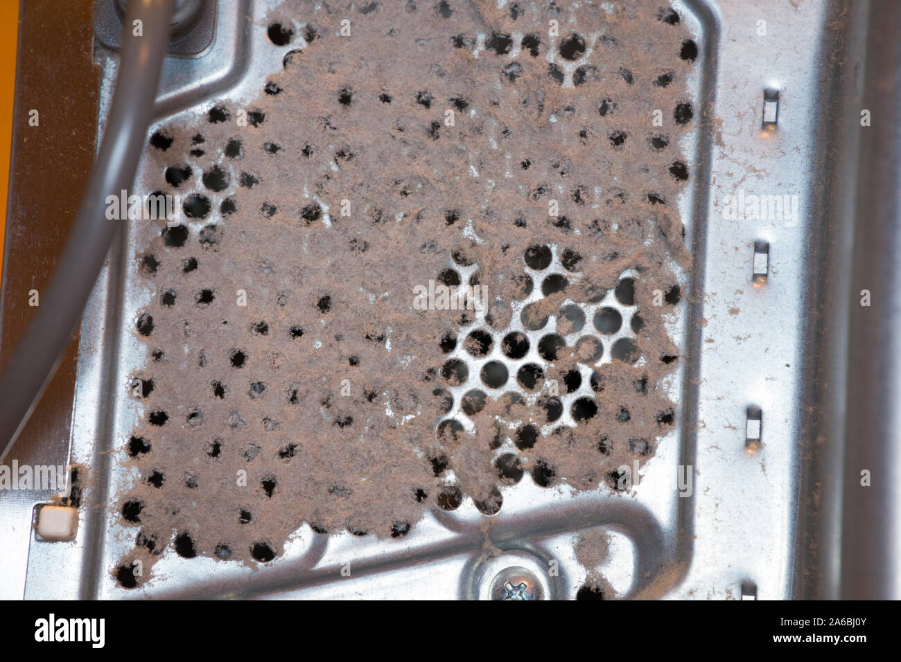 Airborne dust particles & fluff blocking air grille ventilation holes / hole on a kitchen appliance, a microwave. The blocked vent lead to overheating and failure of the oven. UK (105) Stock Photo