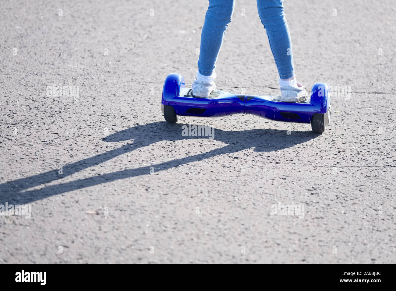 Girl riding blue electric battery powered hoverboard for balance activity close up in summer sun Stock Photo