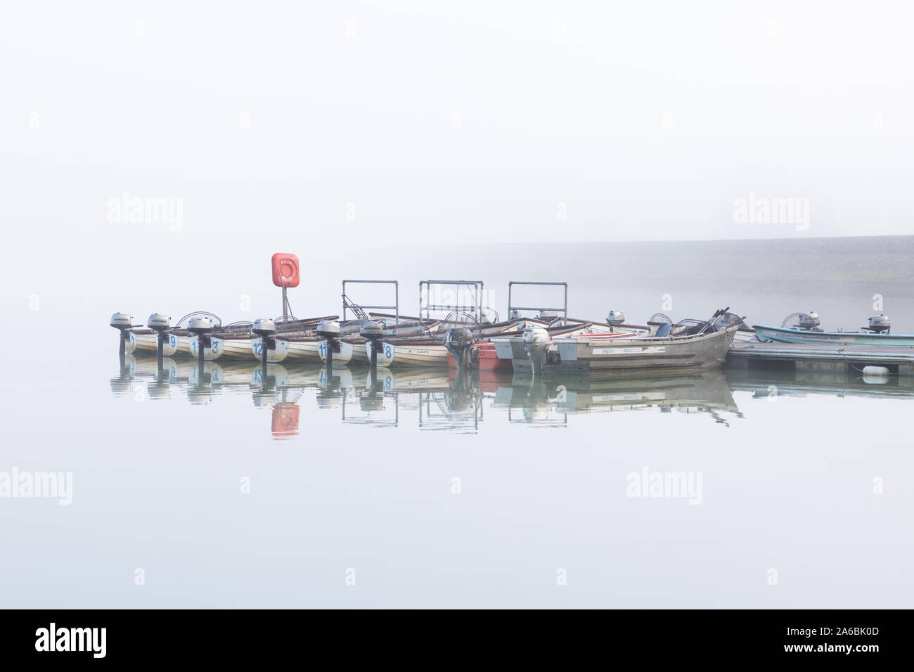 Ravensthorpe Reservoir, Northamptonshire, UK: On a misty morning small angling boats with outboard motors are moored against a pontoon. Stock Photo