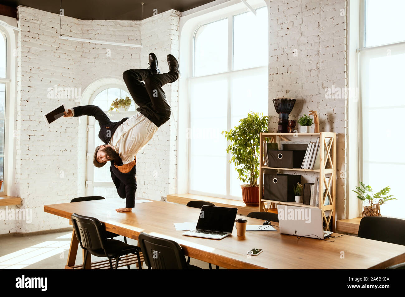 Young caucasian businessman having fun dancing break dance in the