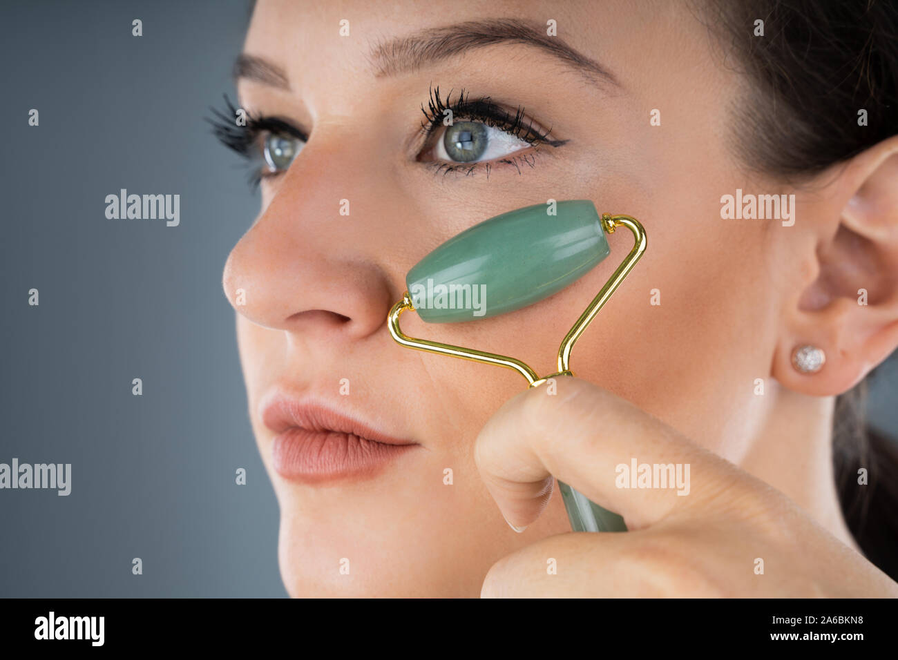 Young Woman Using Jade Roller On Her Face Stock Photo