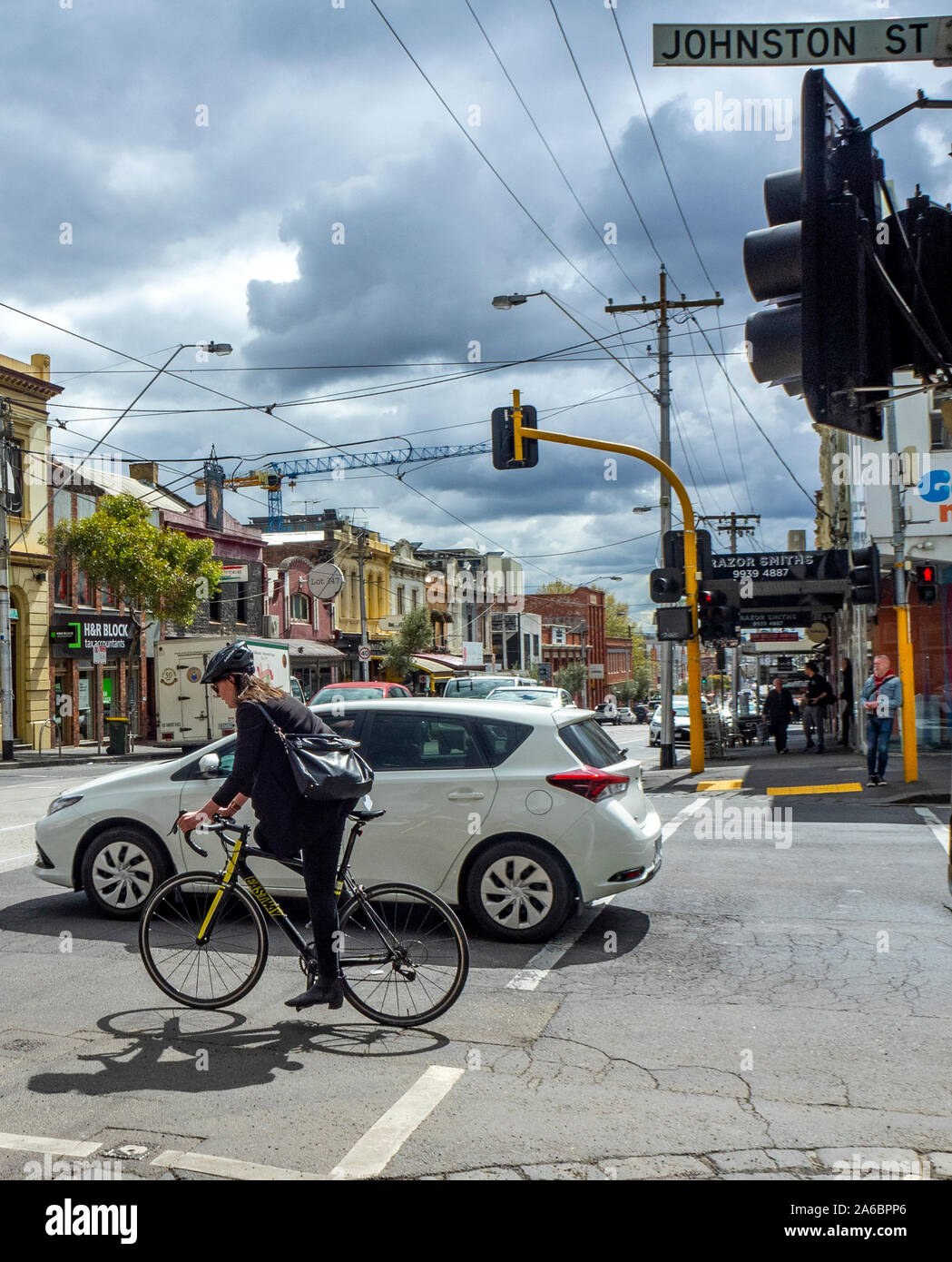 Female cyclist riding her bicycle along Johnston St crossing Smith St Collingwood Melbourne