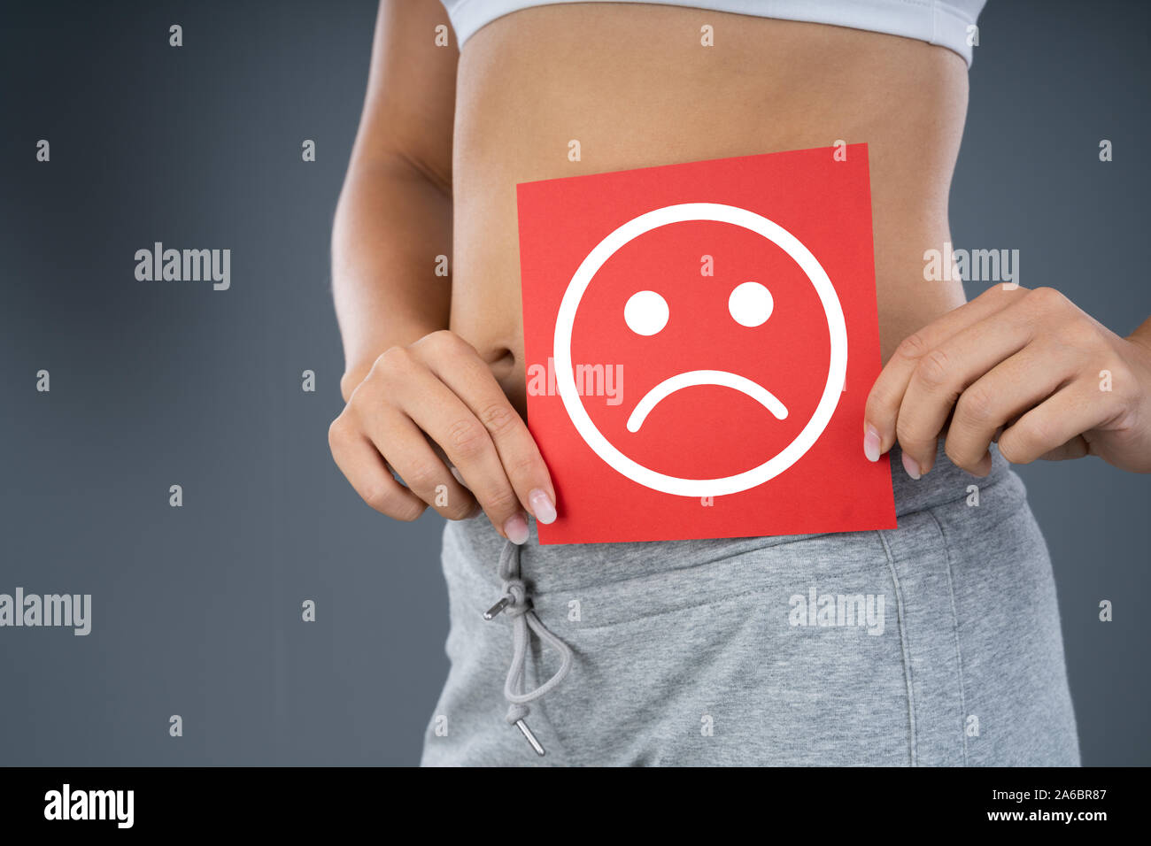 Woman With Stomach Pain Showing Sad Sign On Red Piece Of Paper Stock Photo