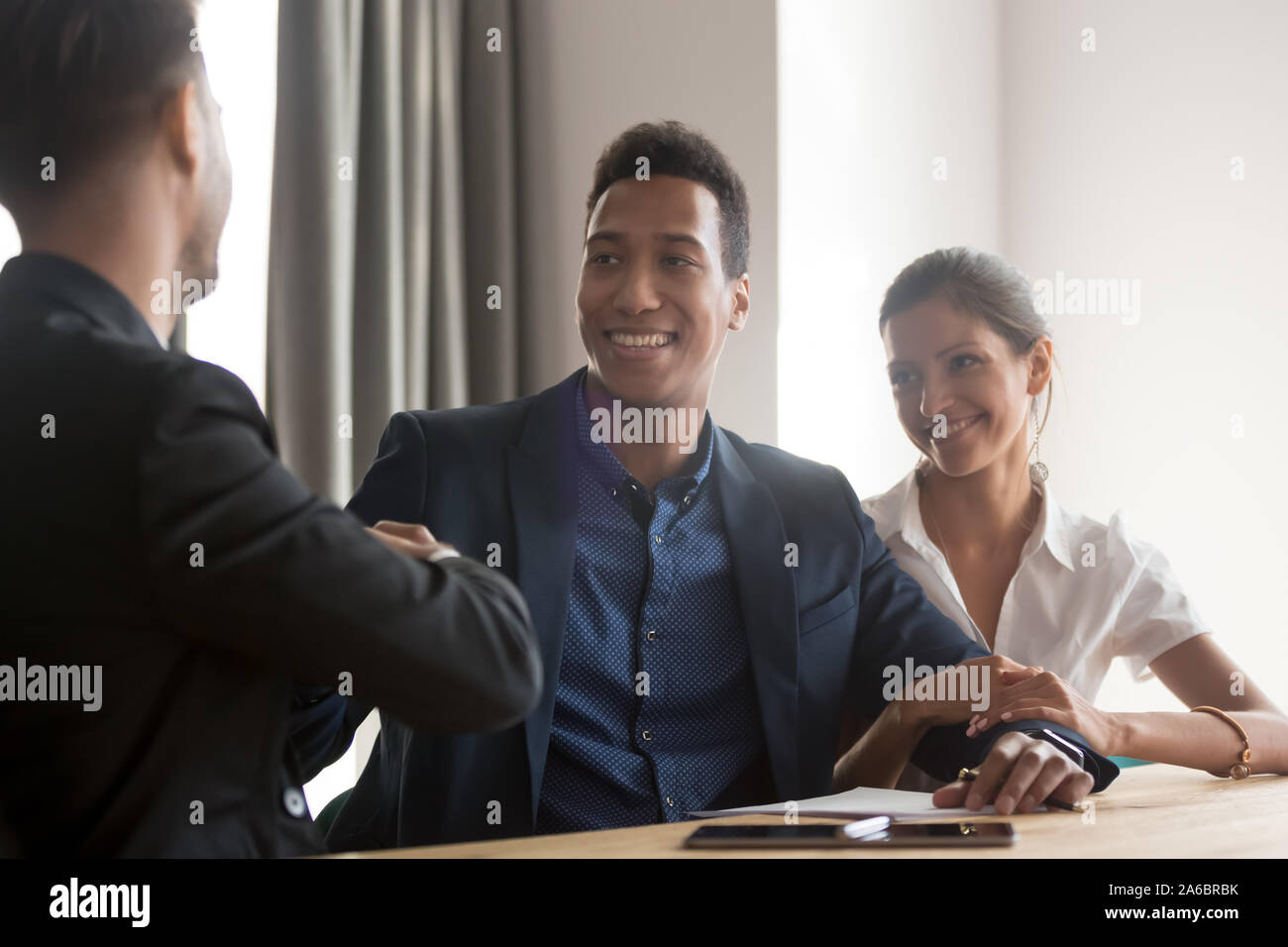 Smiling diverse couple handshaking with financial advisor Stock Photo