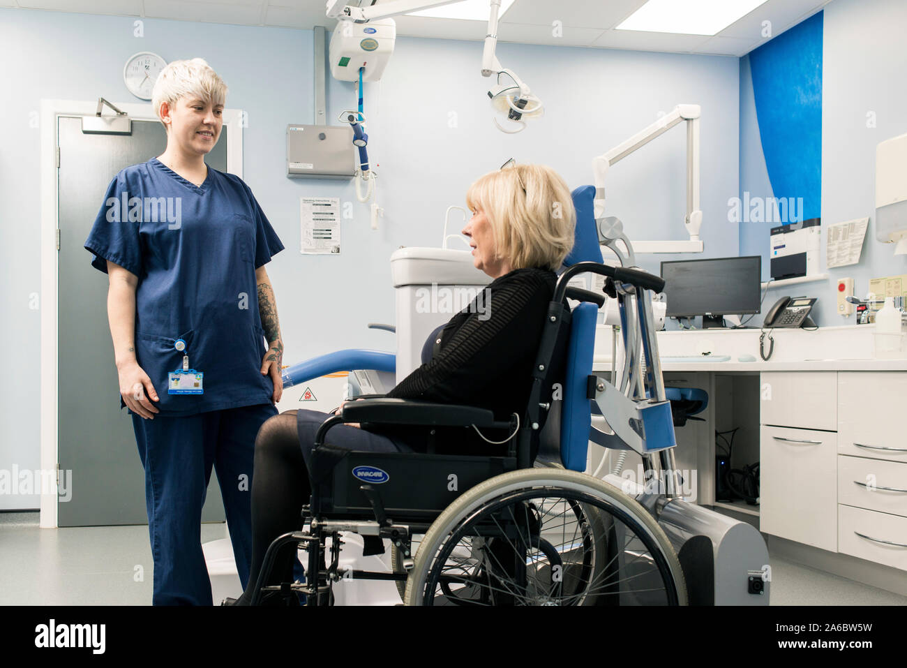 A dental nurse speaks to a disabled patient in a specialist wheelchair