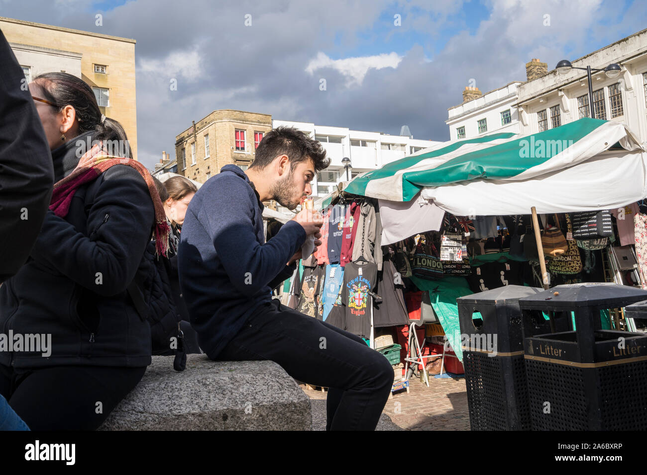 Young man eating filled bread roll in market hill Cambridge 2019 Stock Photo