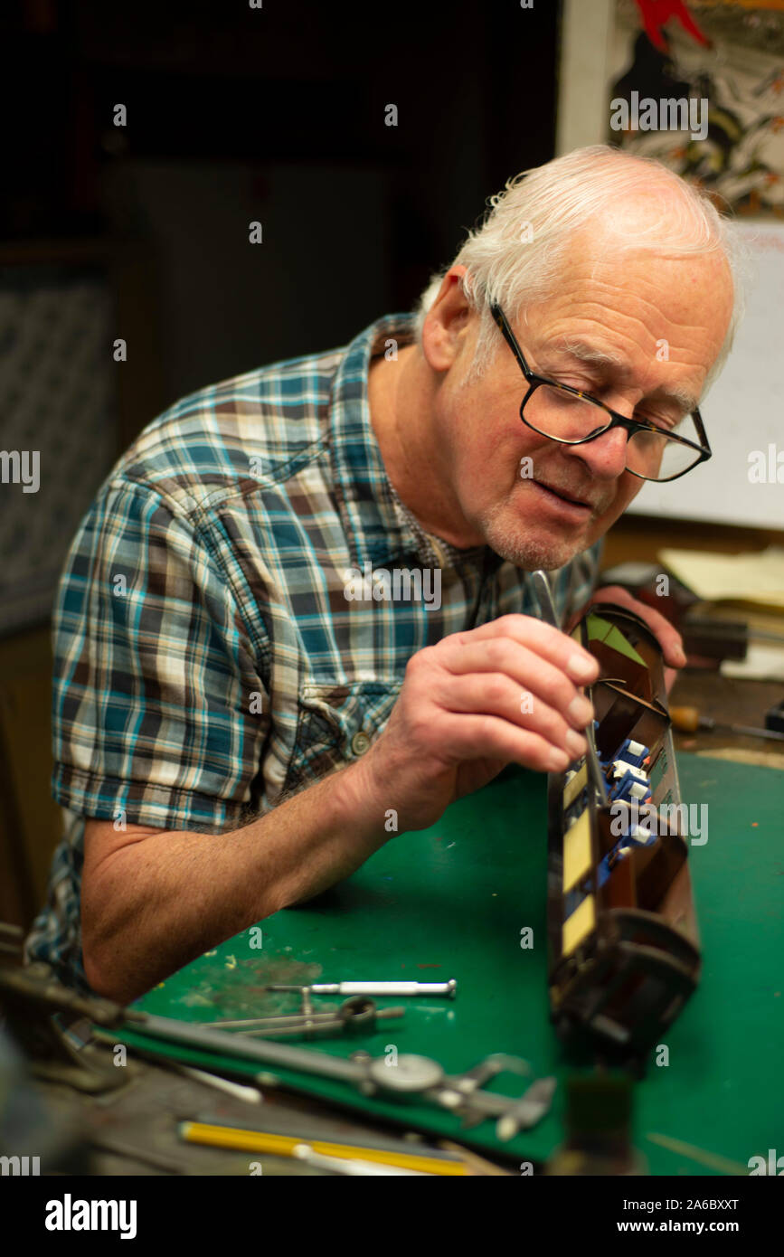 A mature man works on fixing his model train in his shed Stock Photo