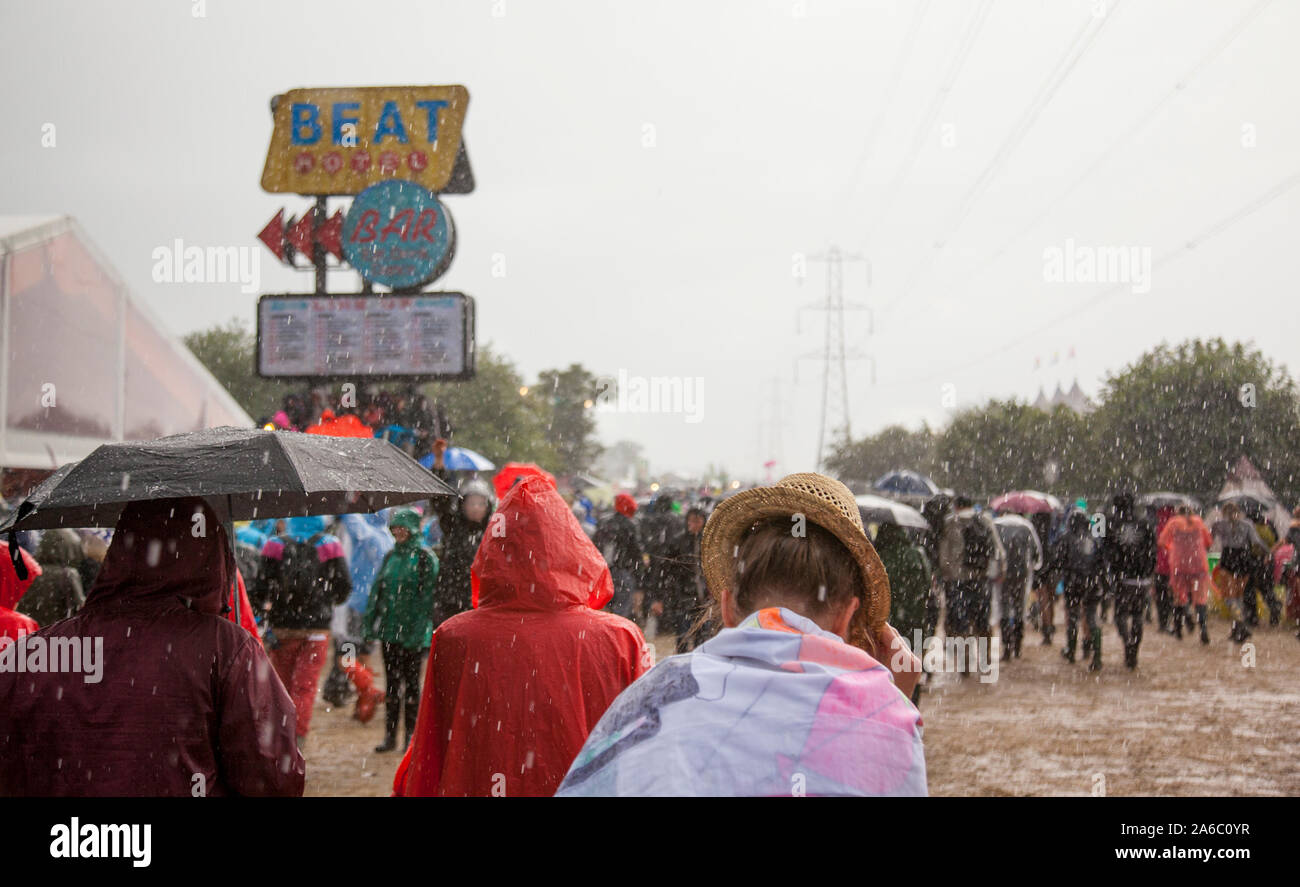 GLASTONBURY, UK - JUNE 27, 2014:  Crowds of people walking past the Beat Hotel at Glastonbury Festival during a heavy rain downpour. Stock Photo