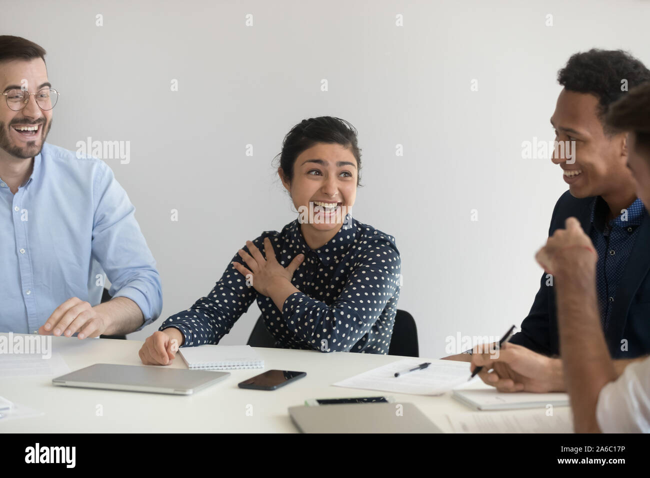 Positive young coworkers discussing project and laughing Stock Photo