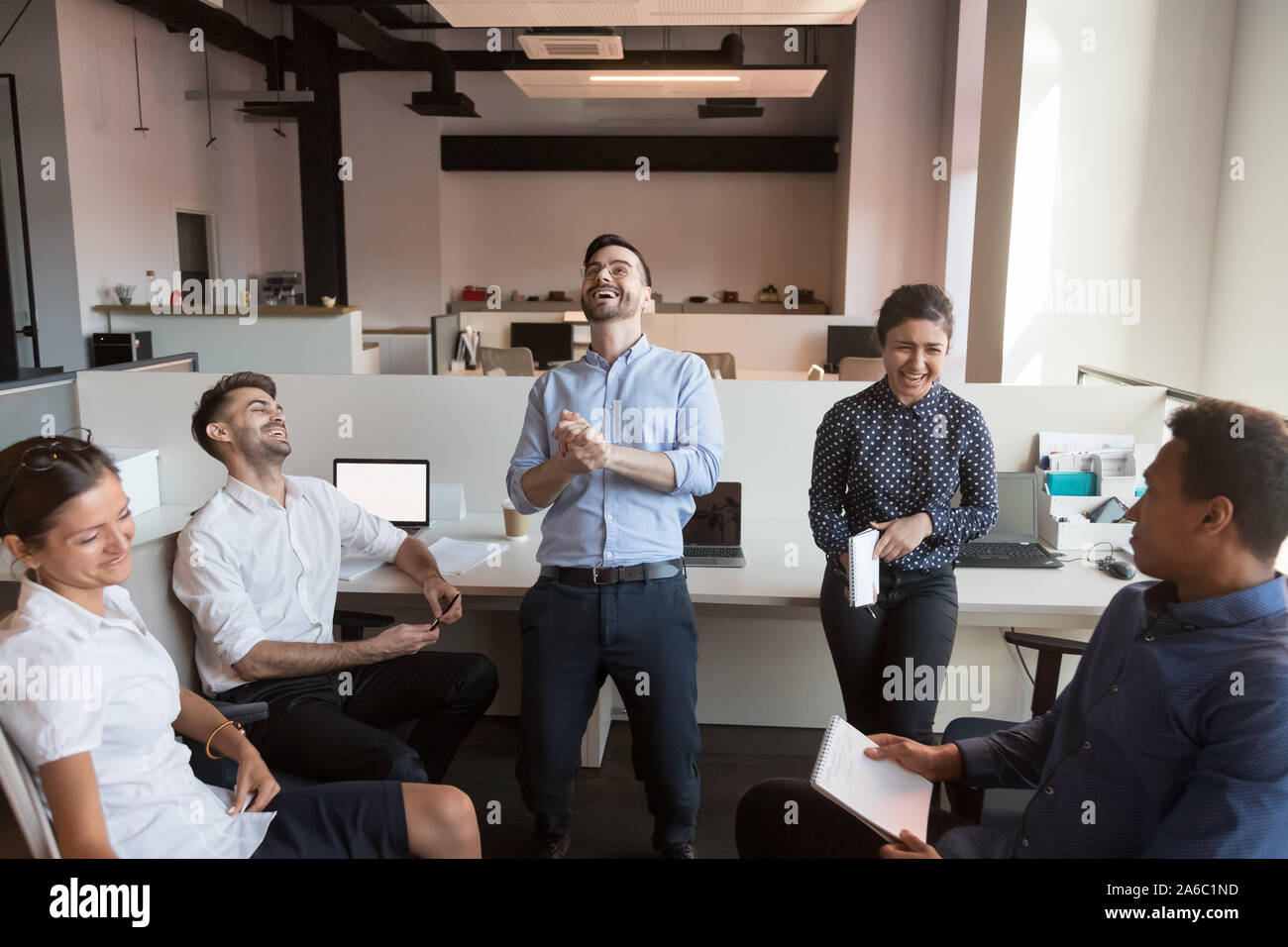 Millennial happy multiracial team joking over teammate Stock Photo